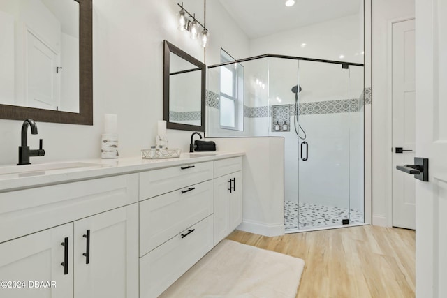 bathroom with hardwood / wood-style flooring, a shower with shower door, and vanity