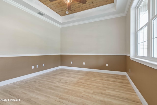 empty room featuring wood ceiling, ornamental molding, ceiling fan, a raised ceiling, and light wood-type flooring