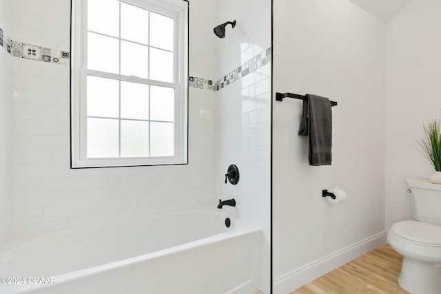 bathroom with tiled shower / bath combo, wood-type flooring, a healthy amount of sunlight, and toilet