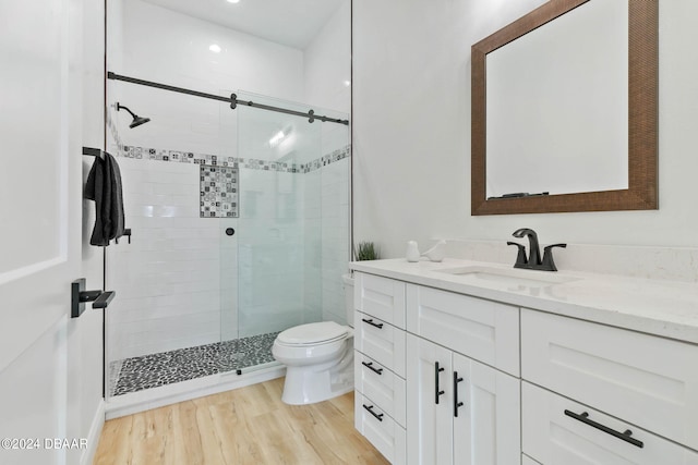 bathroom with walk in shower, vanity, hardwood / wood-style flooring, and toilet