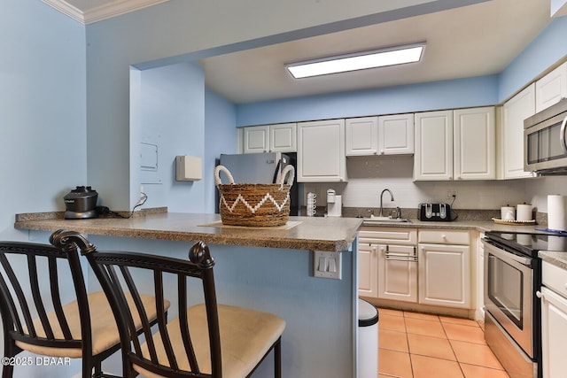 2800 N Atlantic Ave Unit 206, Daytona Beach, FL 32118 - kitchen featuring appliances with stainless steel finishes, a breakfast bar area, a sink, white cabinetry, and ornamental molding