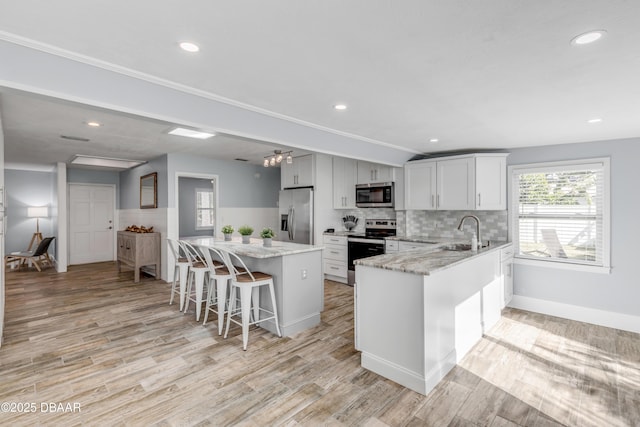 kitchen with light stone counters, sink, a kitchen breakfast bar, and appliances with stainless steel finishes