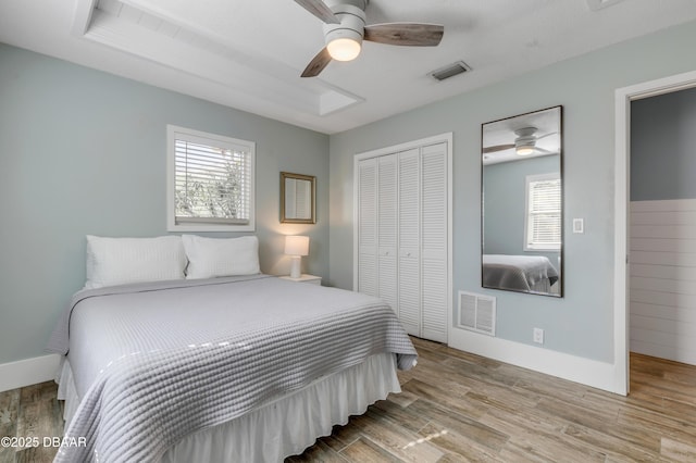 bedroom featuring ceiling fan, a closet, light wood-type flooring, and multiple windows