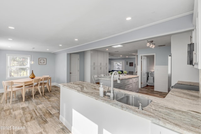 kitchen with light stone countertops, kitchen peninsula, and sink