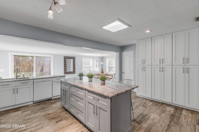 kitchen featuring a center island, a breakfast bar, sink, white dishwasher, and a textured ceiling