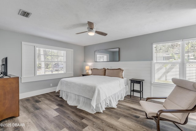 bedroom with ceiling fan, dark hardwood / wood-style floors, and a textured ceiling