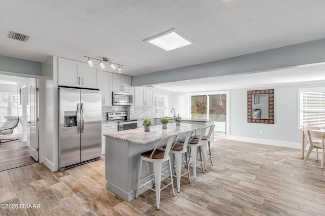 kitchen with light stone countertops, white cabinets, stainless steel appliances, and a breakfast bar