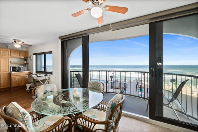 interior space featuring ceiling fan, a water view, a view of the beach, and light tile patterned flooring