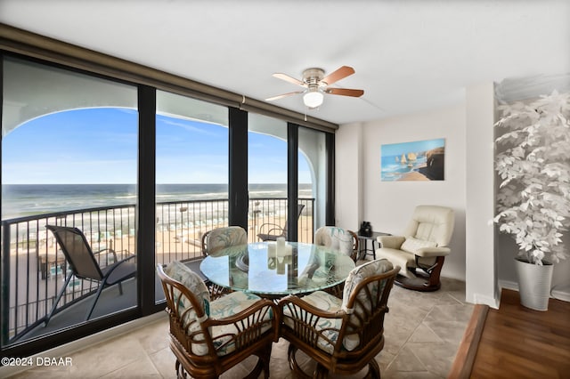 sunroom featuring a beach view, a water view, and ceiling fan