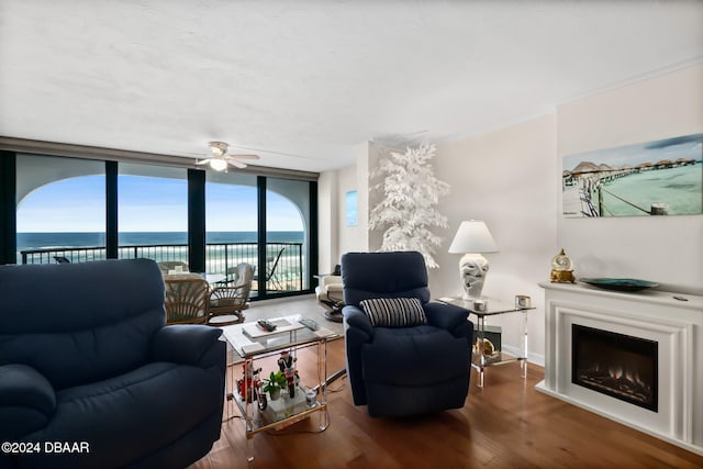 living room with ornamental molding, a wall of windows, hardwood / wood-style flooring, a water view, and ceiling fan