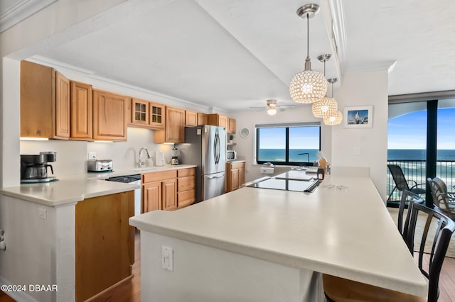 kitchen featuring a water view, kitchen peninsula, light hardwood / wood-style flooring, decorative light fixtures, and stainless steel fridge