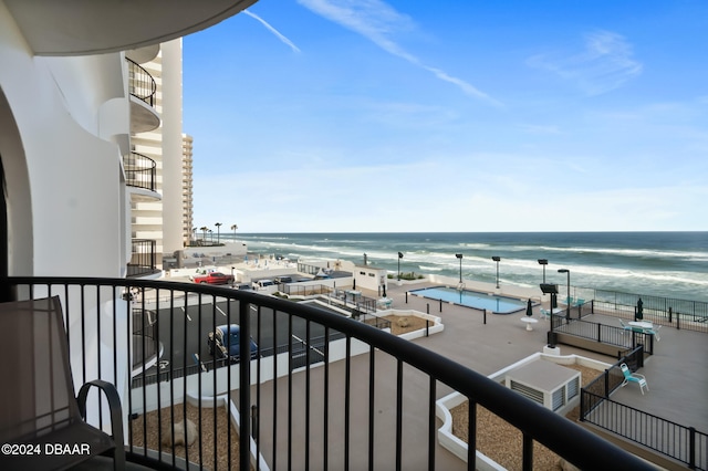 balcony with a water view and a view of the beach