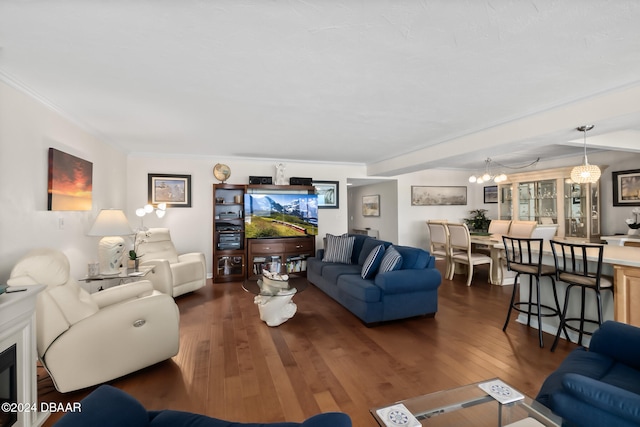 living room featuring ornamental molding, dark wood-type flooring, and a notable chandelier