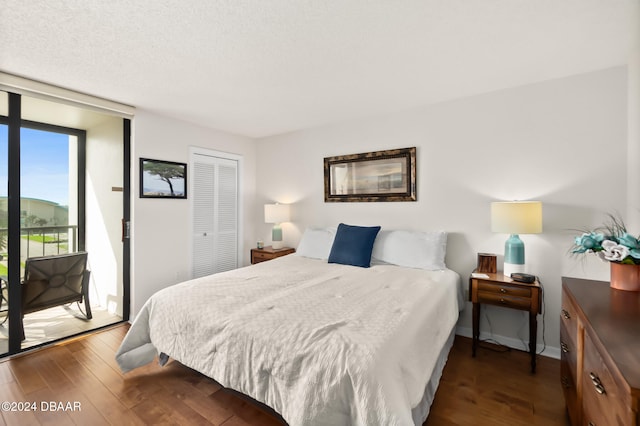 bedroom with dark hardwood / wood-style floors, a textured ceiling, a closet, and access to outside