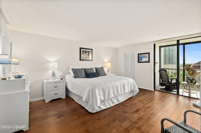 bedroom with access to outside, dark wood-type flooring, a textured ceiling, and a closet