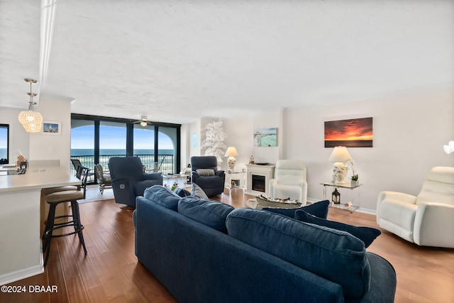 living room with dark wood-type flooring, a water view, and floor to ceiling windows