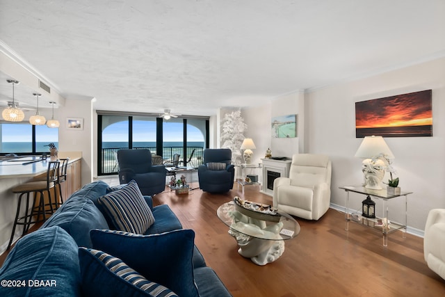 living room featuring wood-type flooring, crown molding, floor to ceiling windows, a water view, and ceiling fan