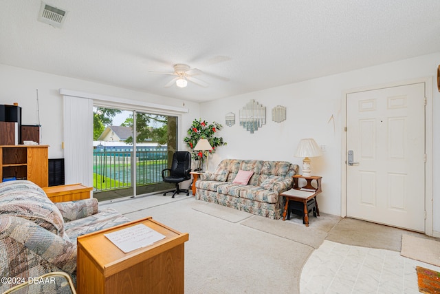 living room with a textured ceiling, light colored carpet, and ceiling fan