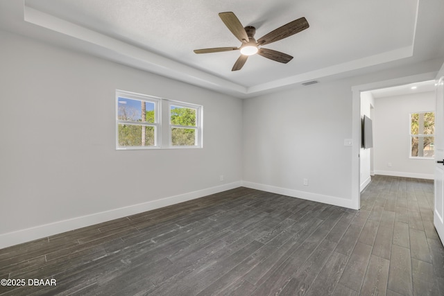 182 Howes St, Oak Hill, FL 32759 - empty room with a tray ceiling, visible vents, a ceiling fan, and dark wood finished floors