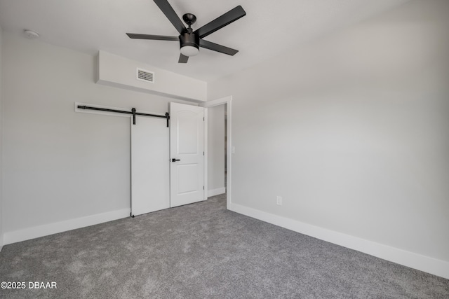 182 Howes St, Oak Hill, FL 32759 - unfurnished bedroom featuring a barn door, carpet floors, baseboards, and visible vents