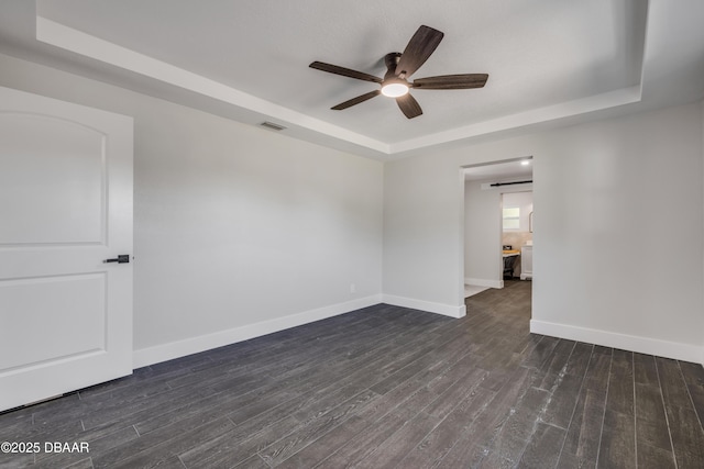 182 Howes St, Oak Hill, FL 32759 - empty room featuring a tray ceiling, baseboards, dark wood finished floors, visible vents, and a ceiling fan