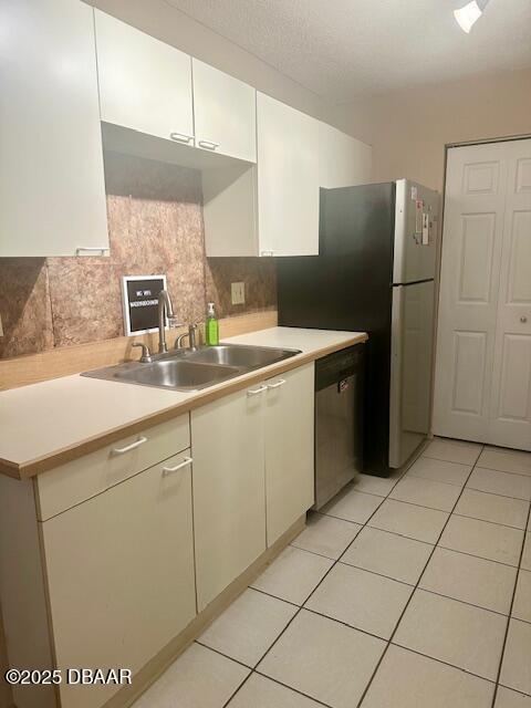 kitchen featuring dishwasher, light countertops, decorative backsplash, white cabinets, and a sink