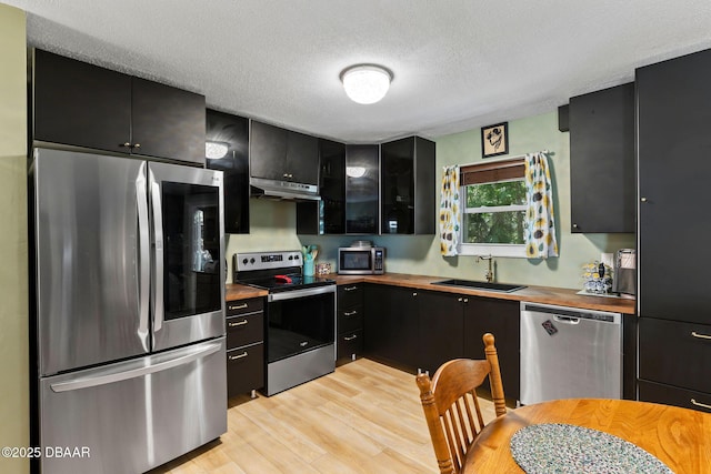 292 Fir St, Ormond Beach, FL 32174 - kitchen with stainless steel appliances, butcher block counters, a sink, under cabinet range hood, and dark cabinetry
