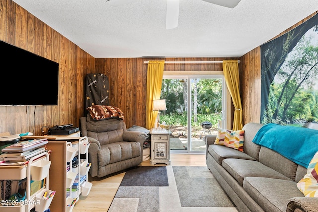 292 Fir St, Ormond Beach, FL 32174 - living room featuring wooden walls, a textured ceiling, a ceiling fan, and light wood-type flooring