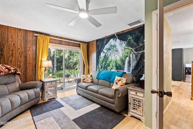 292 Fir St, Ormond Beach, FL 32174 - living room with ceiling fan, light wood-style flooring, a textured ceiling, and wood walls