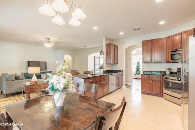 tiled dining space featuring ceiling fan with notable chandelier and sink