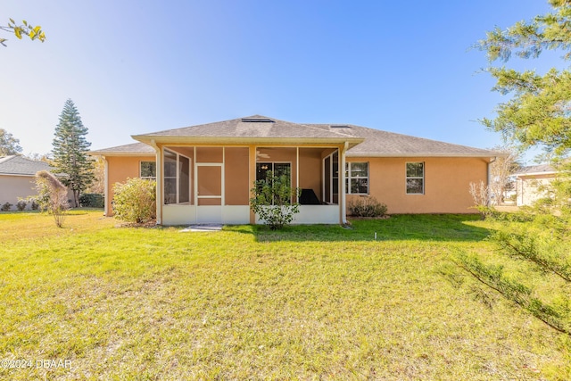 rear view of house with a lawn and a sunroom