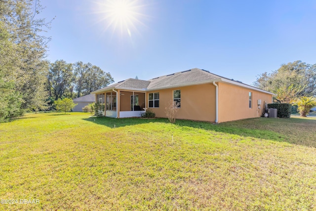 back of property with a sunroom, a yard, and central air condition unit