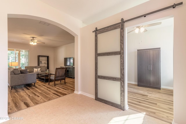 interior space with a barn door, ceiling fan, and light hardwood / wood-style floors