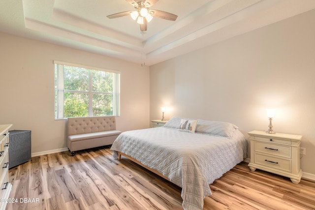 bedroom featuring ceiling fan, light hardwood / wood-style floors, a raised ceiling, and radiator heating unit