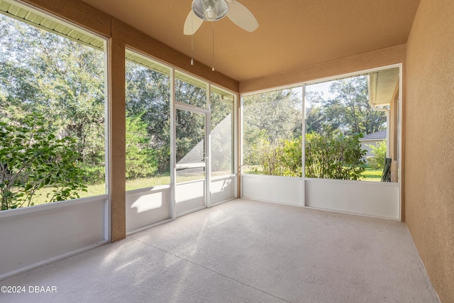 unfurnished sunroom featuring ceiling fan and a healthy amount of sunlight