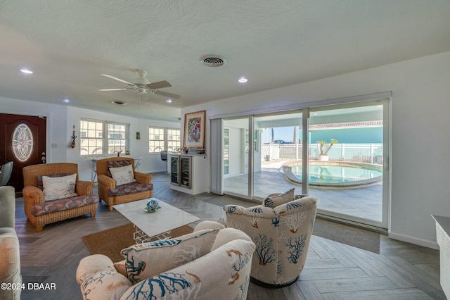 living room featuring ceiling fan, parquet flooring, beverage cooler, and a textured ceiling