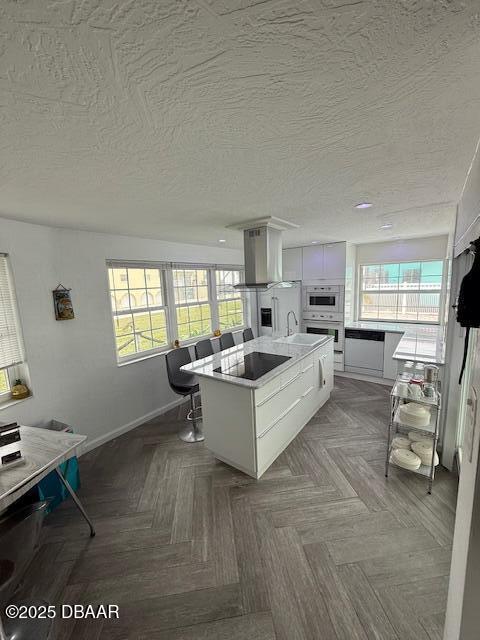 kitchen featuring sink, appliances with stainless steel finishes, a wealth of natural light, white cabinets, and a kitchen island