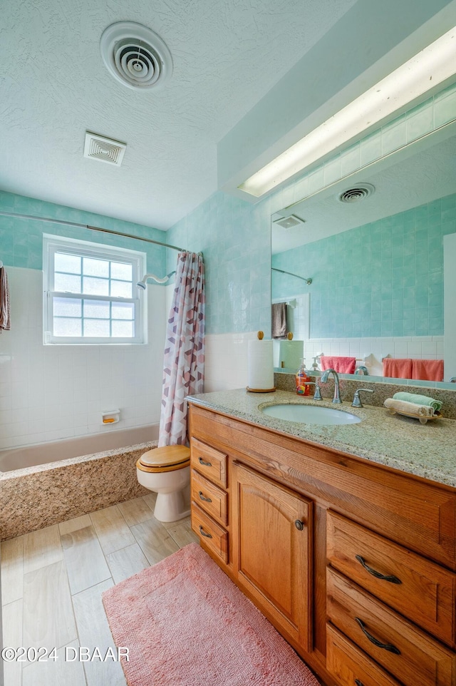 full bathroom with vanity, toilet, shower / bath combo with shower curtain, and a textured ceiling