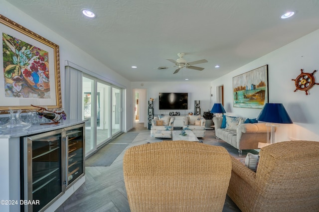 living room with wine cooler, bar, a textured ceiling, ceiling fan, and light parquet floors