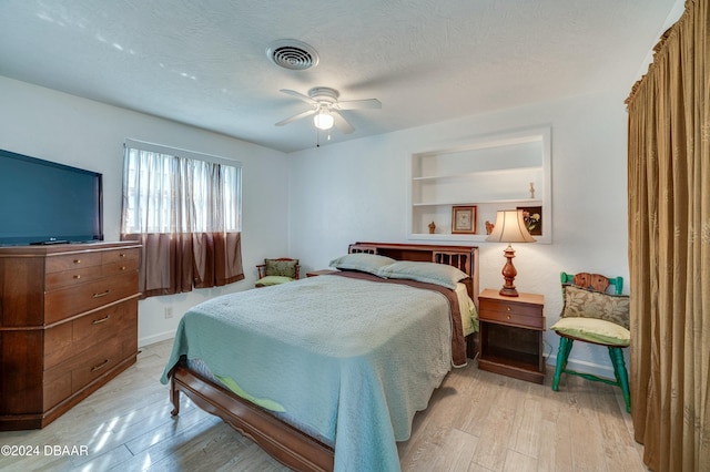 bedroom with a textured ceiling, ceiling fan, and light hardwood / wood-style floors