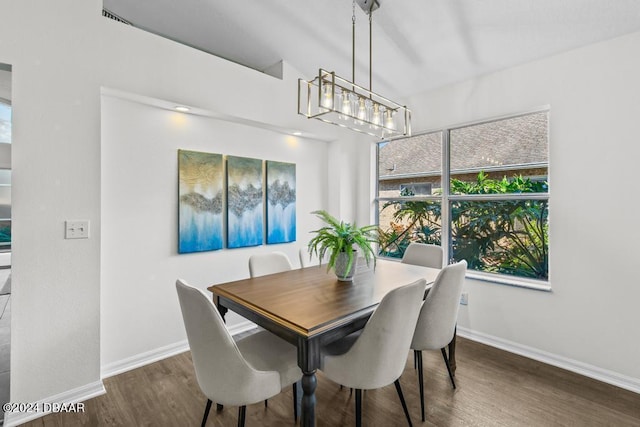 dining space with baseboards, a notable chandelier, and wood finished floors