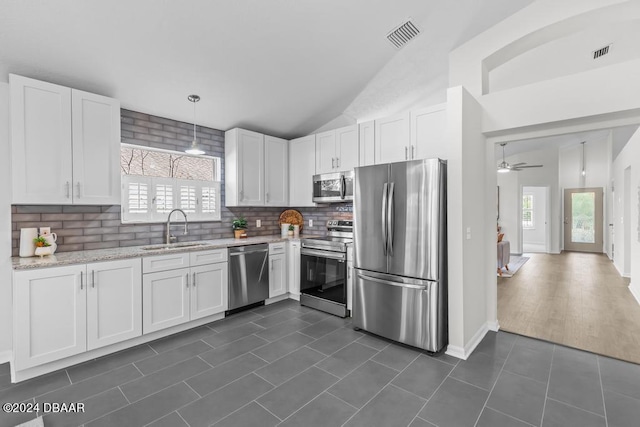 kitchen with dark tile patterned floors, a sink, white cabinetry, stainless steel appliances, and decorative backsplash