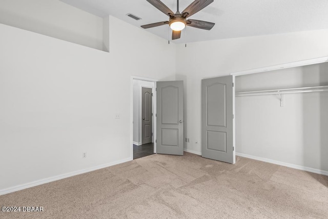 unfurnished bedroom with baseboards, visible vents, carpet floors, lofted ceiling, and a closet