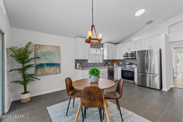 dining area featuring a wealth of natural light, baseboards, dark tile patterned floors, and vaulted ceiling