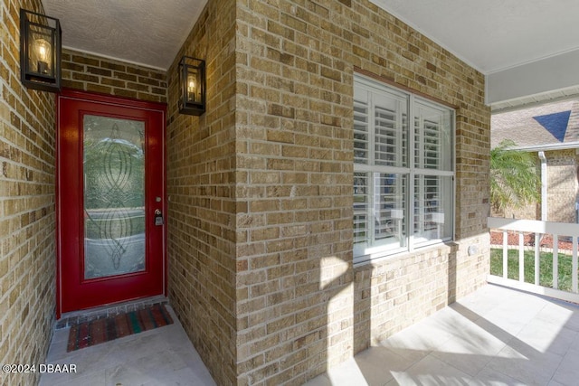 doorway to property with brick siding and covered porch