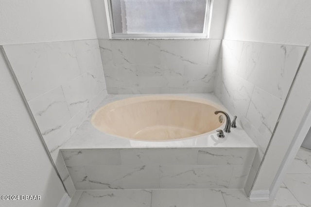 full bathroom featuring a bath and marble finish floor