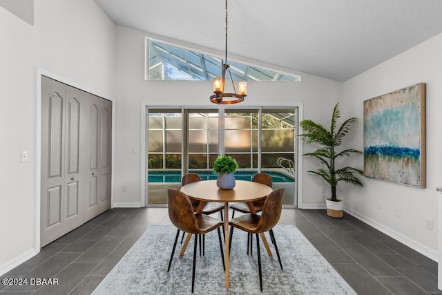 dining space featuring an inviting chandelier, baseboards, lofted ceiling, and dark tile patterned flooring