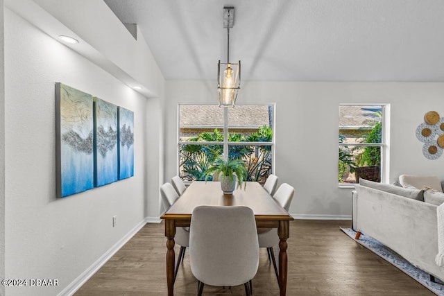 dining room with baseboards, wood finished floors, and vaulted ceiling