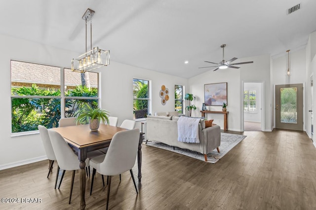 dining space featuring visible vents, baseboards, wood finished floors, and vaulted ceiling