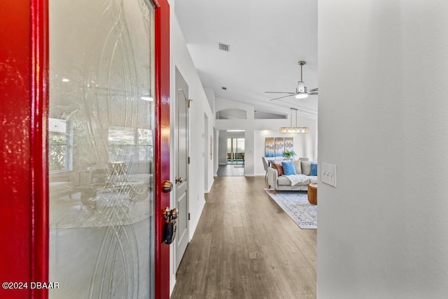 entryway featuring wood finished floors, baseboards, visible vents, vaulted ceiling, and ceiling fan with notable chandelier